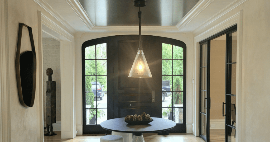 Dramatic black ceiling in a modern entryway with elegant molding and natural light.