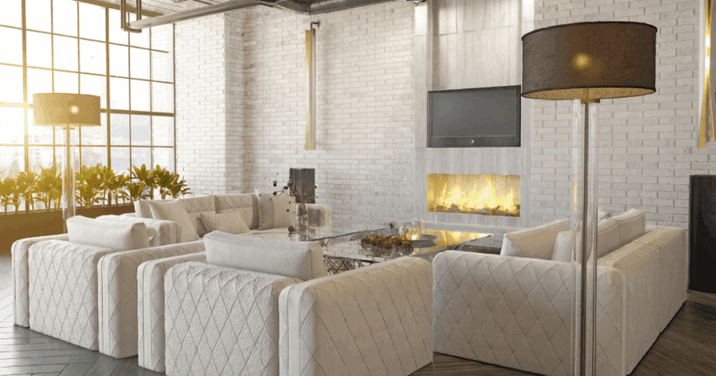 Modern industrial living room featuring white limewash brick walls, neutral-toned upholstered seating, and a sleek linear fireplace.