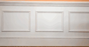 Elegant white wainscoting and baseboards in a finished interior wall.
