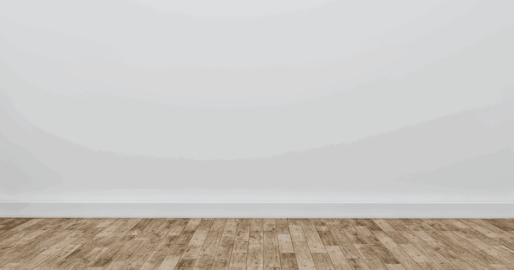 Empty interior room with freshly painted baseboards along a clean white wall.