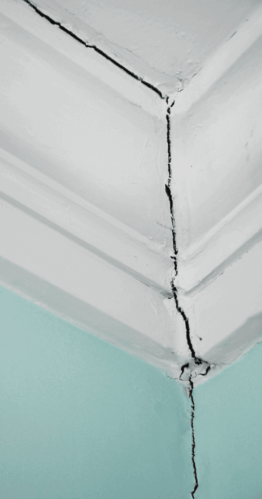 A vertical and horizontal drywall crack in the corner of a ceiling and wall, highlighting the need for professional drywall repair.