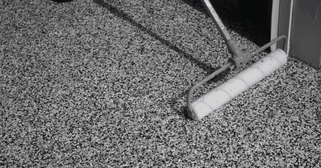 Close-up of a roller applying flake floor coating on concrete to demonstrate commercial floor coating options
