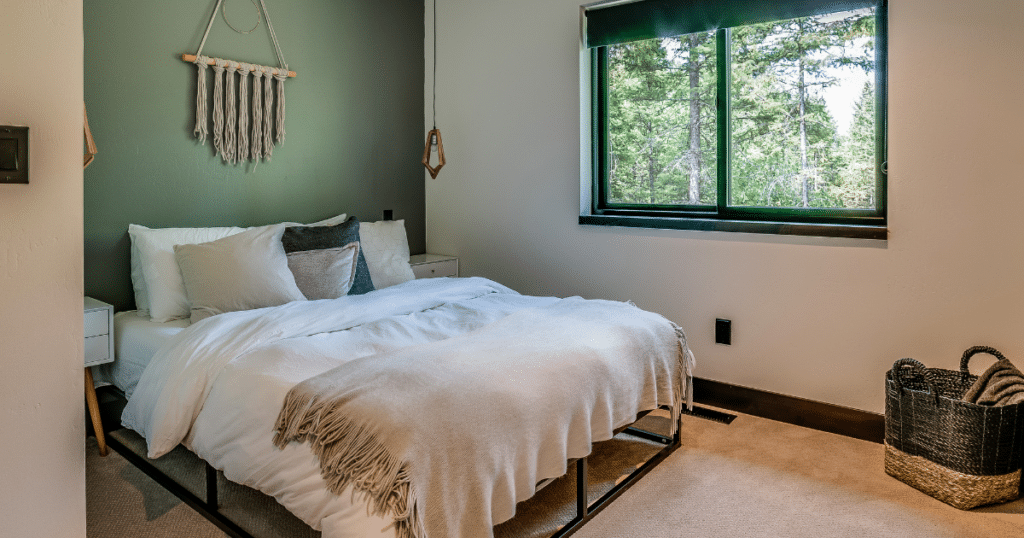 For creative indoor painting projects, check out this bedroom with olive-green accent wall, white bedding, and macramé wall hanging, creating a natural, serene environment.