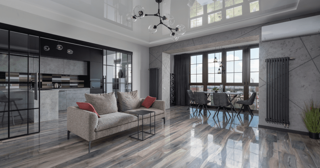 Modern living room with glossy gray flooring, plush sofas, and a wall-to-wall window providing ample natural light.