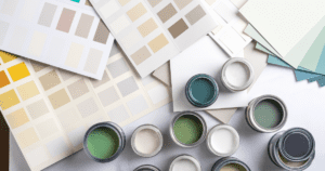 Paint cans and color swatches laid out on a table, showing shades of green, beige, and yellow.