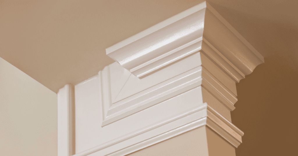 Close-up of white crown molding with intricate design and a smooth, glossy finish, showcasing precise craftsmanship.