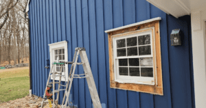 Exterior wall and window trim partially prepped with primer, showcasing the progress of a professional painting project.