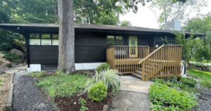Completed exterior home painting with rich, dark siding and clean trim lines surrounded by lush landscaping.