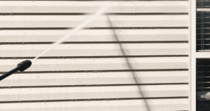 Powerwashing vinyl siding on a home to prepare for painting.