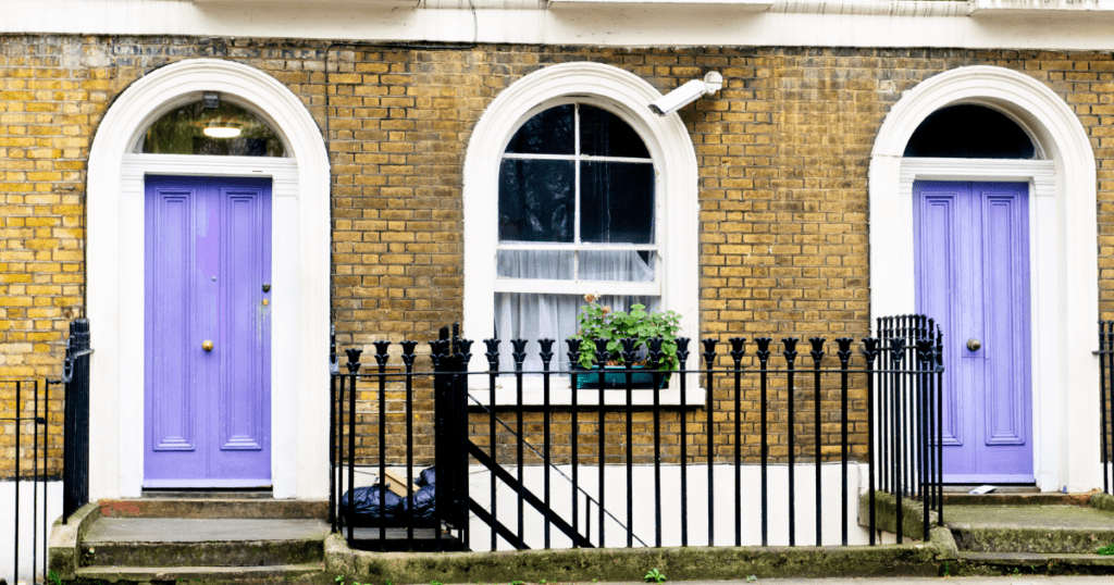 Matching lavender front doors on adjacent historic brick rowhouses with arched white trim.