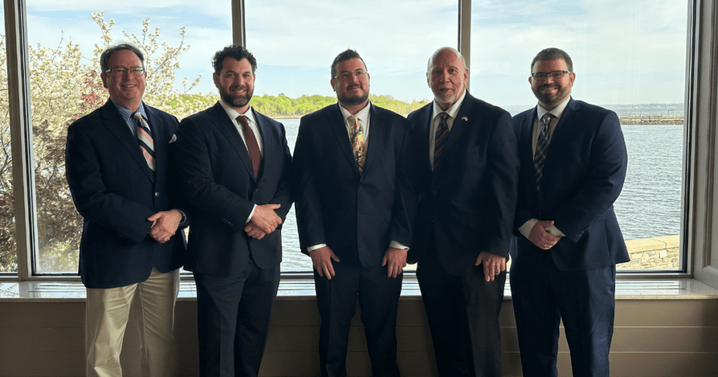From left to right, Carey Hollander, Paul Viggiano, Nick Williams, George Williams Sr., and George Williams Jr. from A.G. Williams Painting Company stand together in front of a scenic waterfront view.