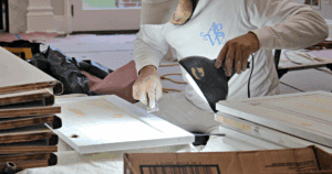 Craftsman meticulously preparing a cabinet door for painting under work light.