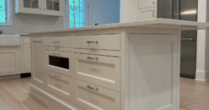 Cream kitchen island with polished hardware and unfinished drawer fronts.