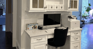 Custom home office area with white cabinetry, marble countertop, and built-in computer station.