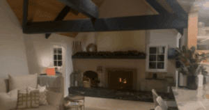 Warm and inviting living room with vaulted ceiling, exposed beams, and a modern fireplace.