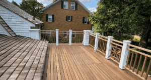 A freshly stained rooftop deck with crisp white trim and natural wood railings overlooking a suburban neighborhood.