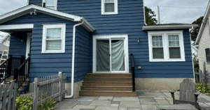 Blue house with freshly painted siding and clean white trim, featuring a back entrance with a sliding door and new stairs.