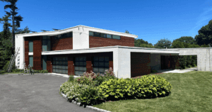 Modern home with white stucco and richly stained wood siding, surrounded by manicured landscaping.