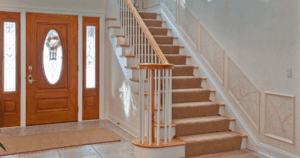 Bright entryway with stained glass double doors and staircase featuring faux-finish panels.