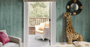 Children's room with green faux wood-grain walls, plush giraffe toy, and view of outdoor deck.