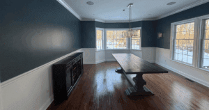 Elegant dining room with two-tone walls in navy and white, crown molding, and large bay windows.