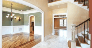 Open foyer and dining space with sage green and beige walls, white wainscoting, and hardwood flooring.