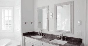 Bright, modern bathroom with dual sinks, marble countertop, and white cabinetry.