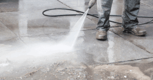 Professional pressure washing in progress, cleaning a concrete surface with high-powered water spray.