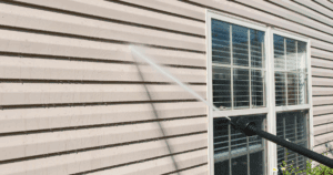 Pressure washing beige vinyl siding on a residential home, removing surface grime and buildup.