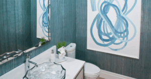 Contemporary half bath with textured blue wallpaper, modern glass sink, and abstract wall art.