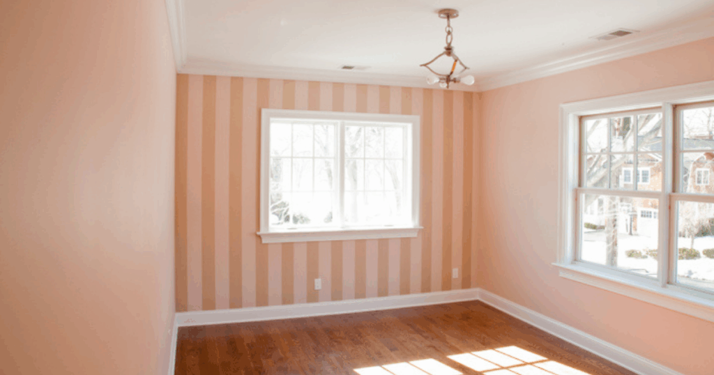 Light-filled room with soft peach vertical striped wallpaper on an accent wall.