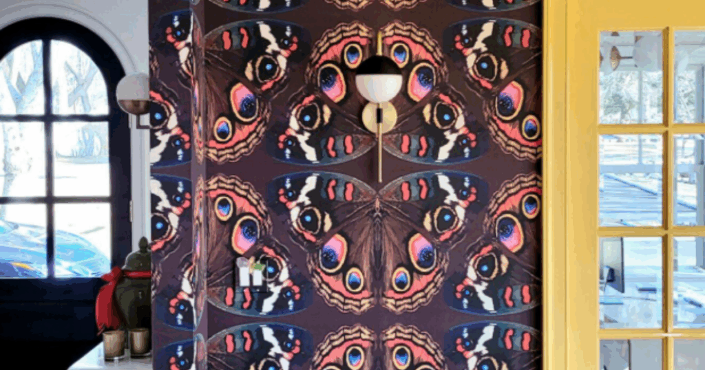 Bold butterfly-themed wallpaper in a vibrant entryway with a modern sconce and colorful accents.