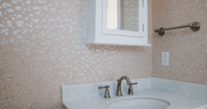 Powder room with soft pink floral wallpaper and a white vanity with marble countertop.