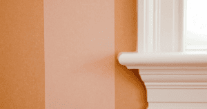Close-up of peach vertical striped wallpaper seamlessly finished against white window trim.