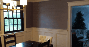 Elegant dining room with two-tone walls—grasscloth wallpaper above white wainscoting.