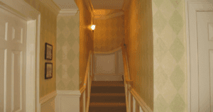 Stairwell with soft green and cream diamond-patterned wallpaper and white trim.