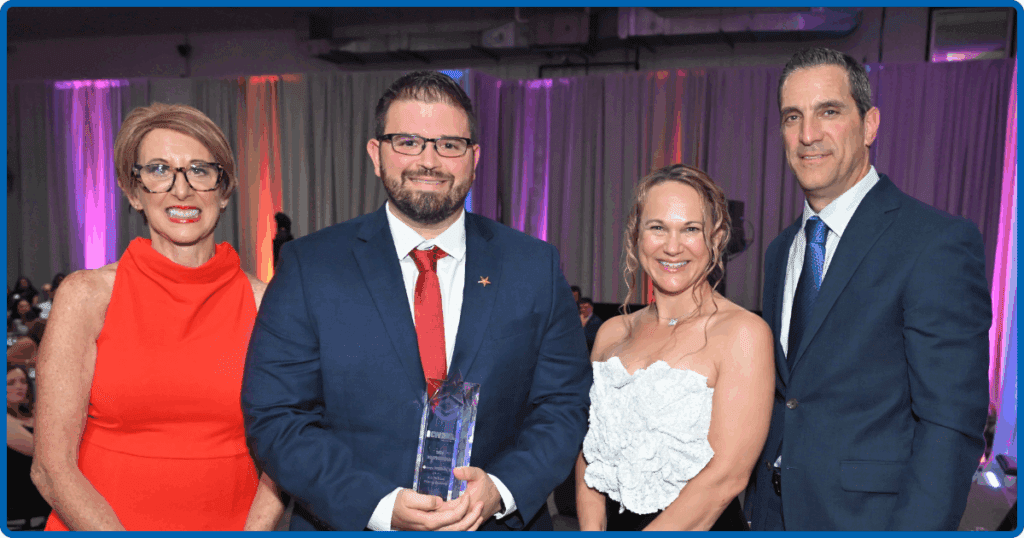 George Williams Jr. stands with three colleagues at the 2024 "40 Under 40 Rising Star Awards," proudly holding an award, dressed in formal attire at a celebratory event.
