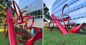 Close-up and wide-angle views of the restored “Thrust” sculpture in Stamford, CT, a large-scale, dynamic red metal artwork by Alexander Liberman, freshly repainted and gleaming outside a commercial office building. It was part of a sculpture restoration project that A.G. Williams completed.
