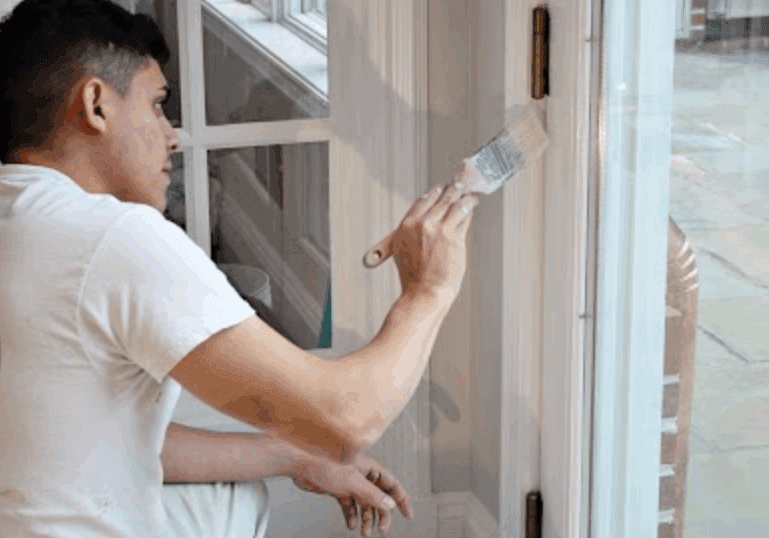 Close-up of a professional A.G. Williams painter carefully applying white paint to a door frame with a precision brush, showcasing painting contractor tips in action. Avoid these common house painting mistakes with tips from A.G. Williams.